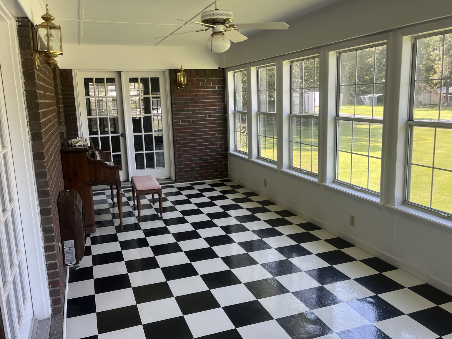 Bright sunroom with black-and-white flooring and walls of windows